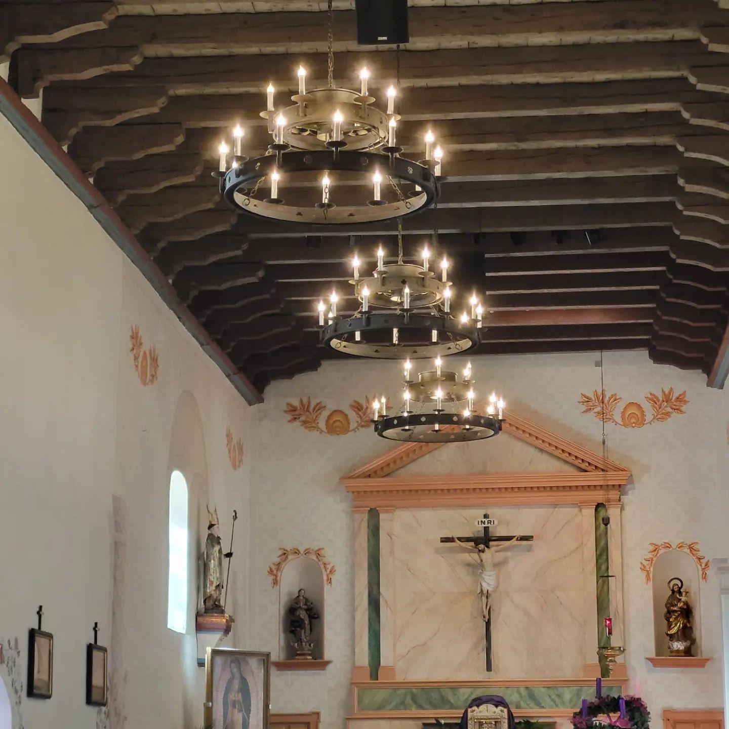 The interior of a lobby with a high ceiling, chandeliers, and religious decorations.